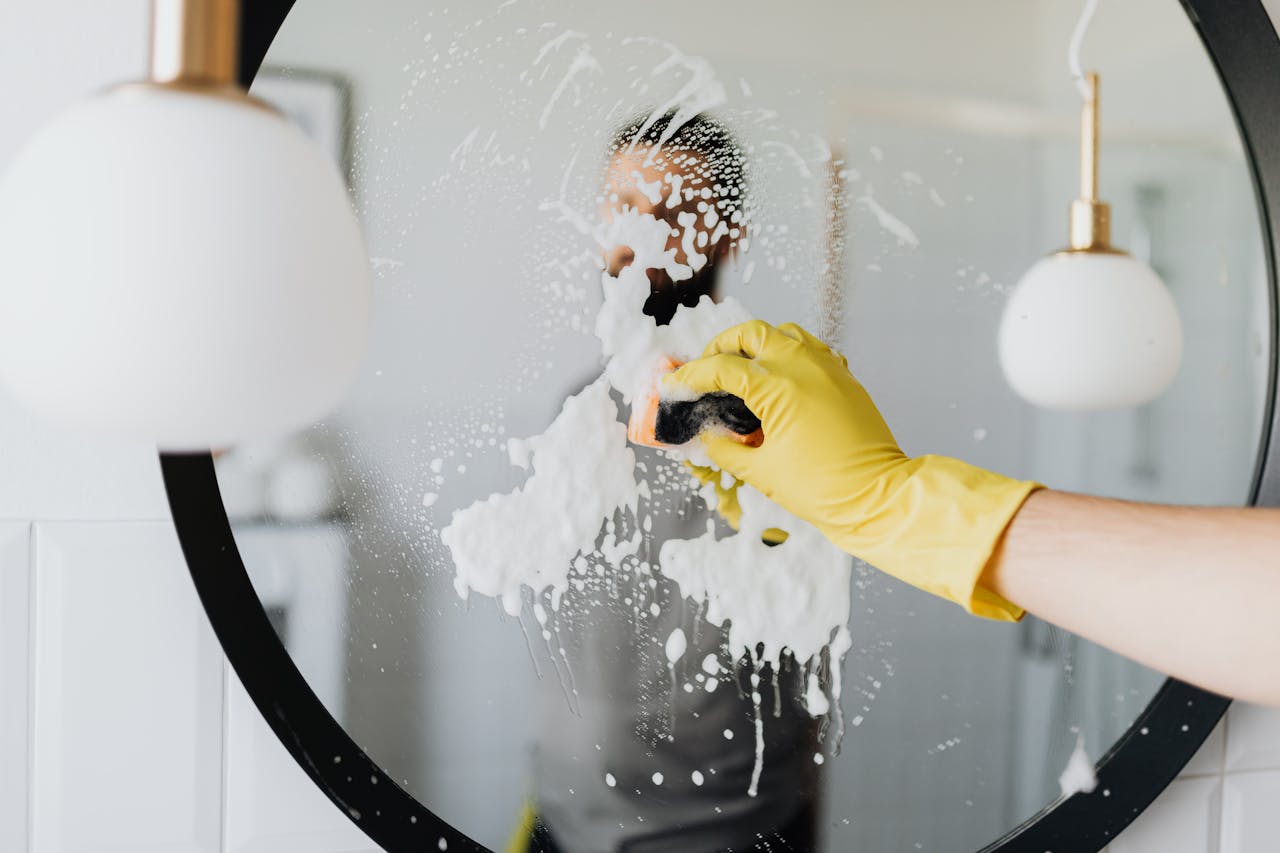 The Art of Drawing Readers In: Your attractive post title goes here Anonymous male housekeeper in yellow rubber gloves wiping foam from round mirror in bathroom