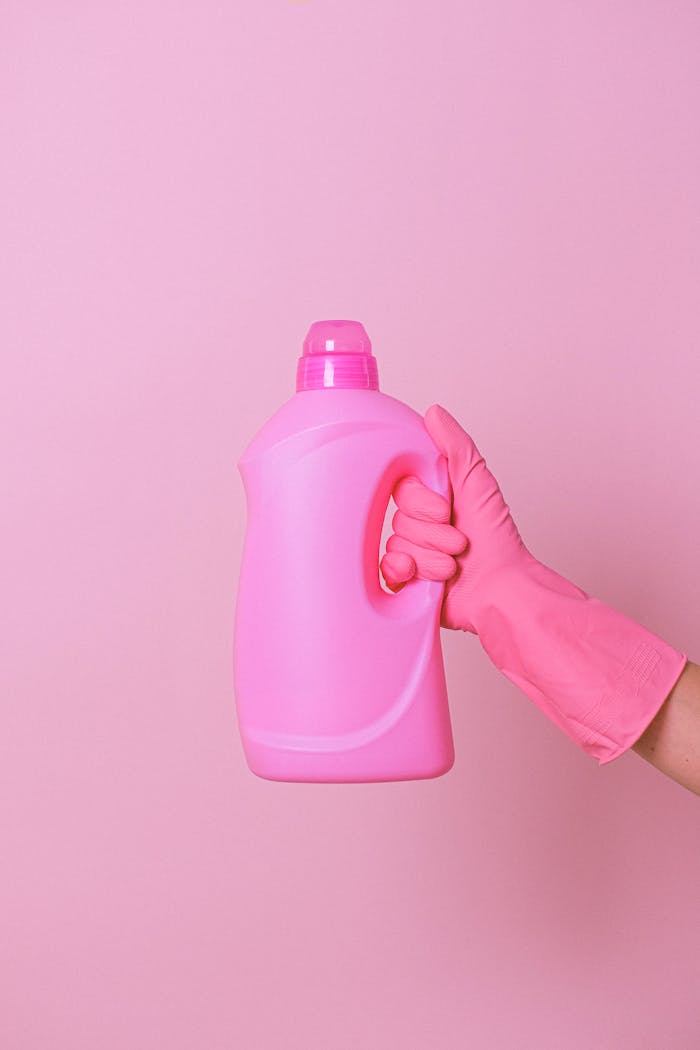 Mastering the First Impression: Your intriguing post title goes here A person holding a pink cleaning product bottle with a pink glove against a pink background.